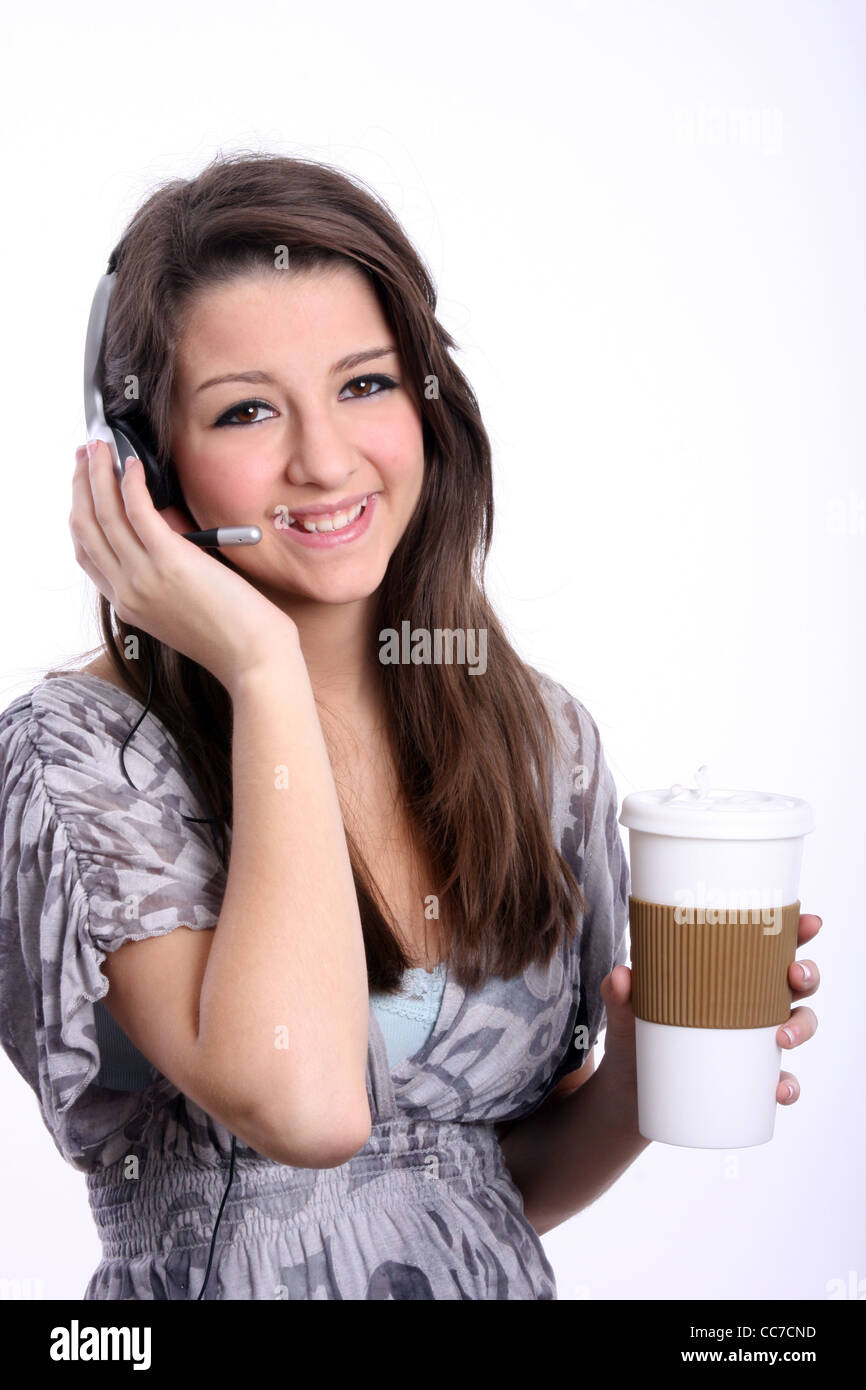 Una giovane donna nel servizio clienti utilizzando un auricolare del telefono con una tazza da caffè Foto Stock