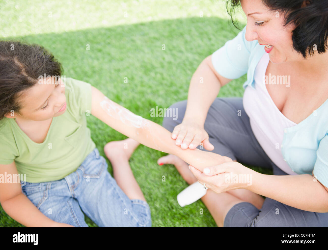 Madre ispanica mettendo sunscreen sulla figlia Foto Stock