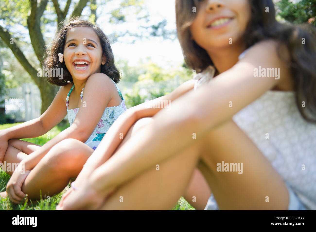 Sorridente ragazza ispanica seduto in erba insieme Foto Stock