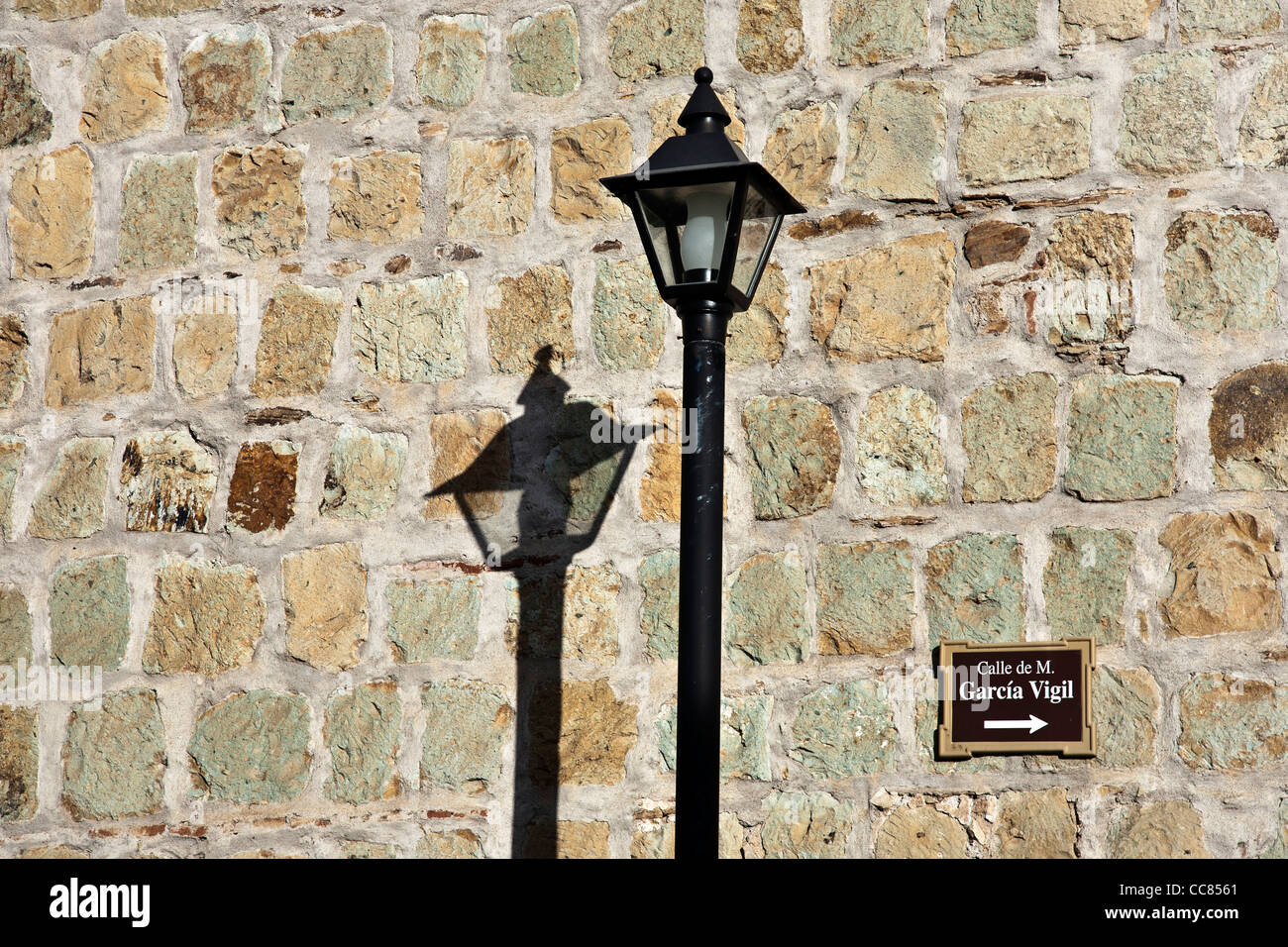 Riproduzione di ferro vintage via lampada & riflessione sul bel vecchio Oaxacan green cantera muro di pietra con un cartello stradale Messico Foto Stock