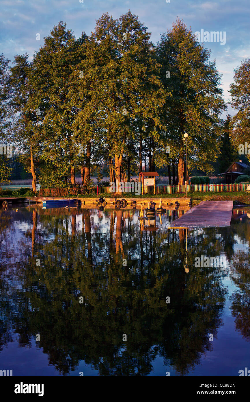 Un alberi e barca è riflesso in clear lake Foto Stock Un alberi e barca è riflesso in clear lake Foto Stock