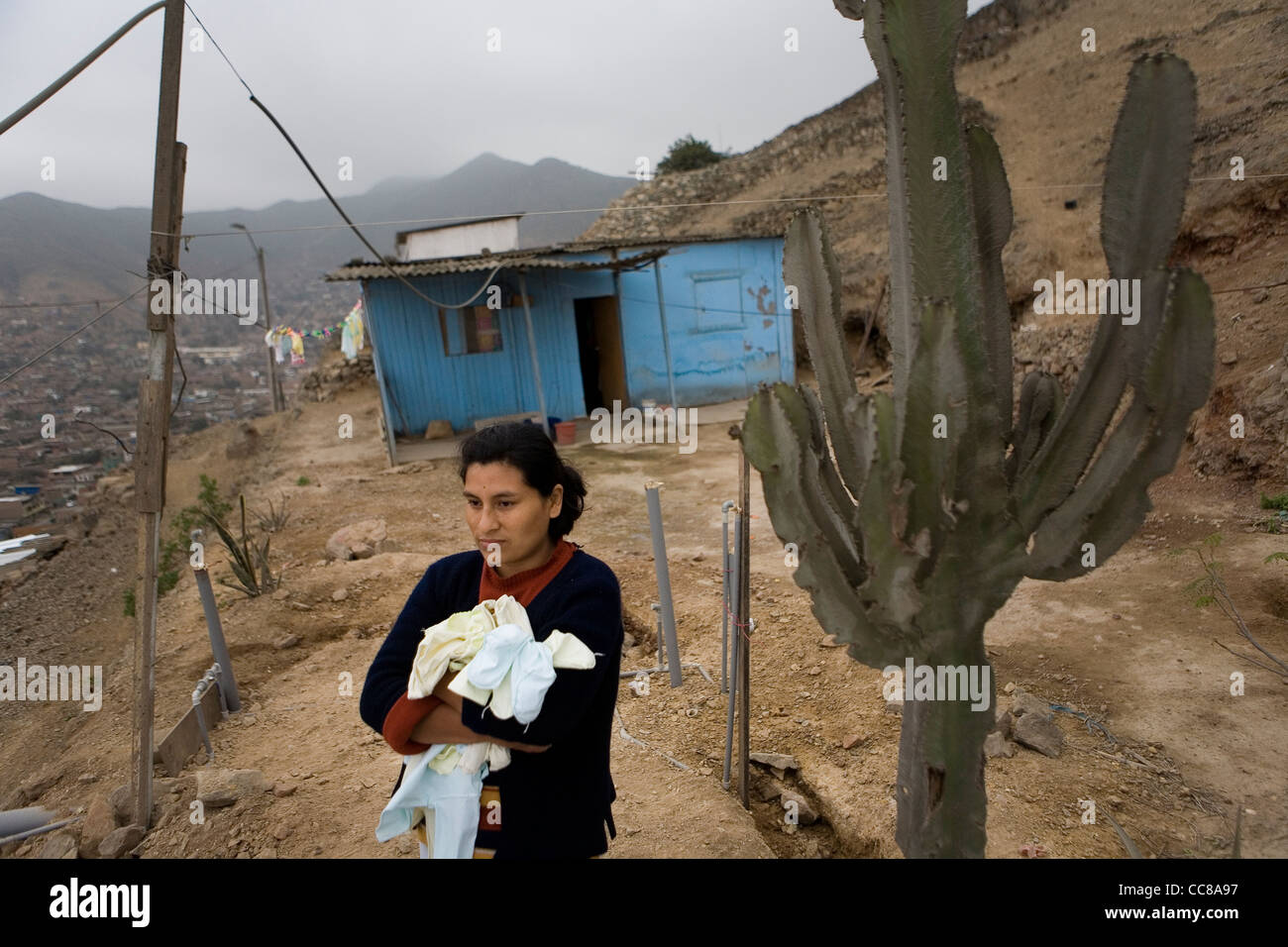 Una donna che sta al di fuori della propria casa in un villaggio squatter in Lima, Perù, Sud America. Foto Stock