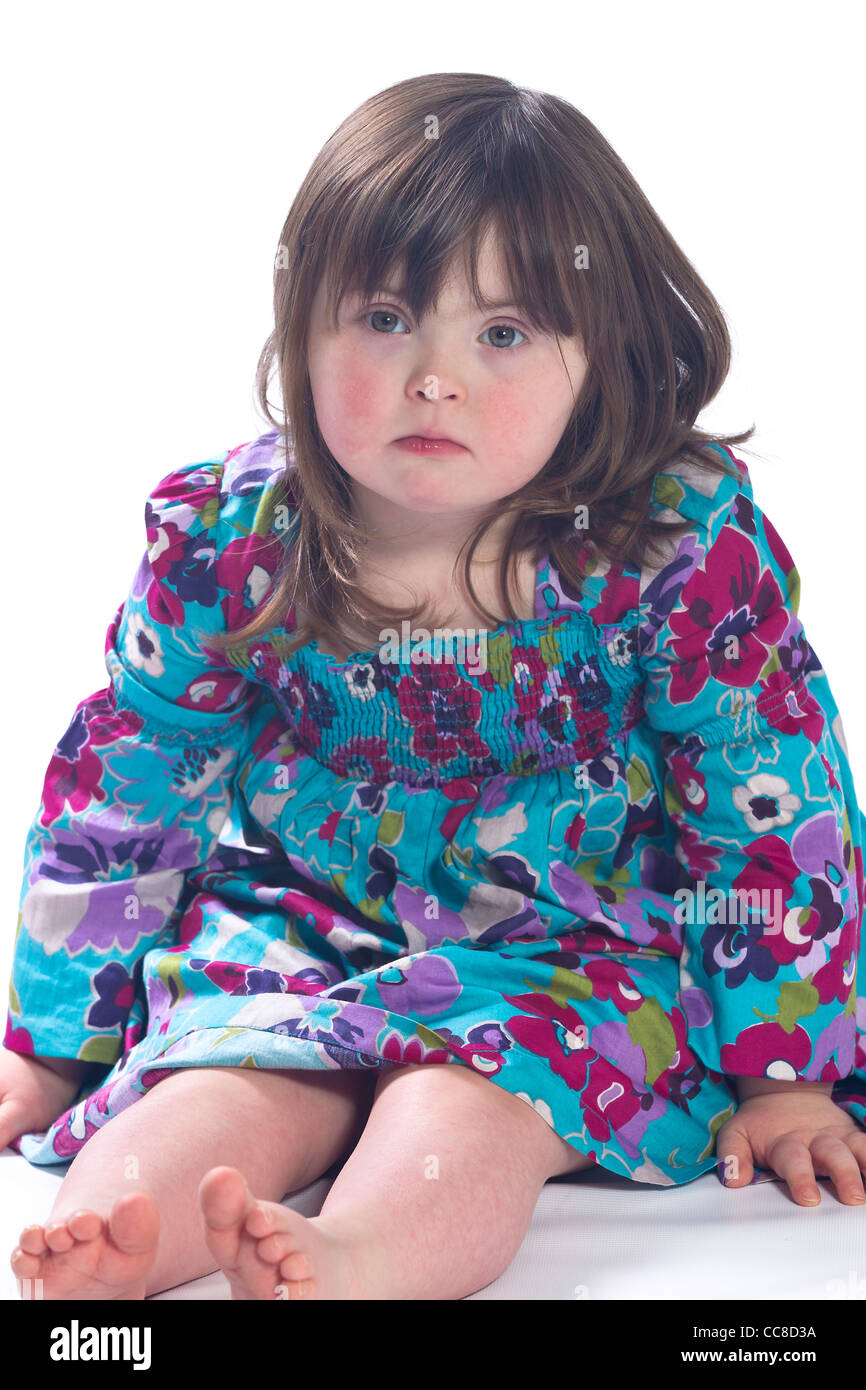 La sindrome di Down ragazza sedeva piedi nudi. Foto Stock