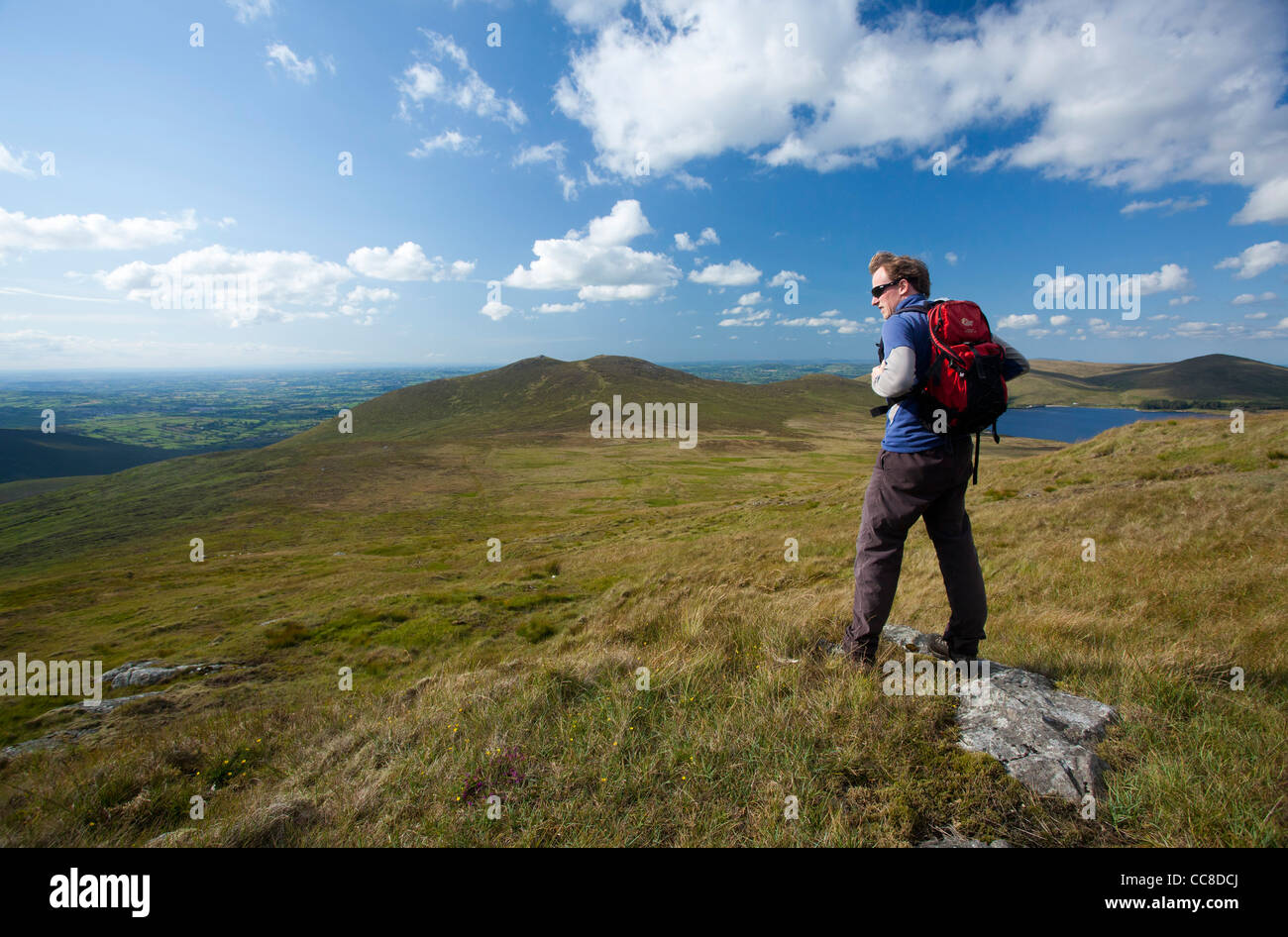 Walker cercando attraverso Spelga e la valle rocciosa da Pigeon Rock Mountain, Mourne Mountains, County Down, Irlanda del Nord. Foto Stock