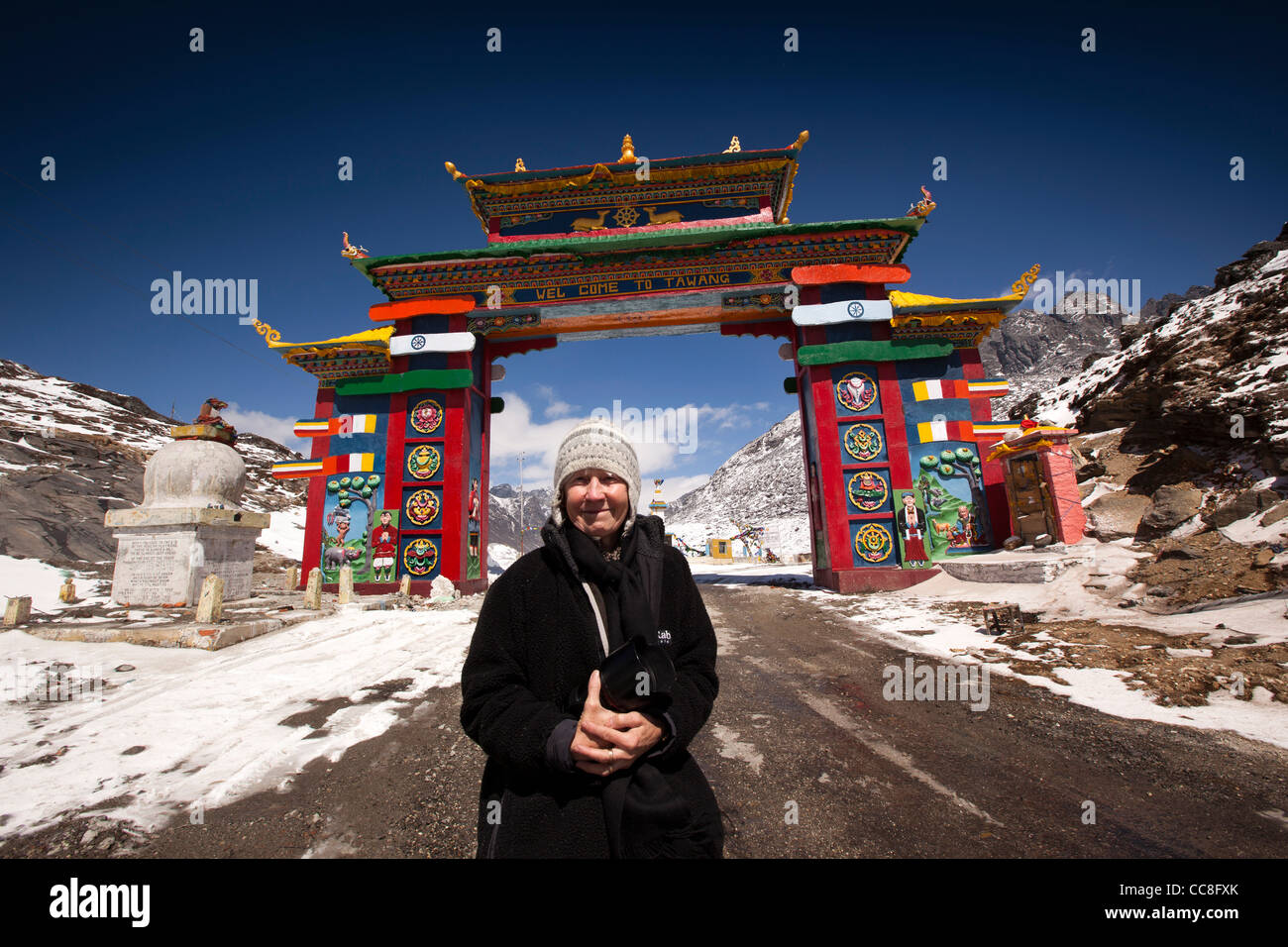 India, Arunachal Pradesh, Sela Pass, turista femminile in alta altitudine road passando sotto il gateway colorati di Tawang Foto Stock