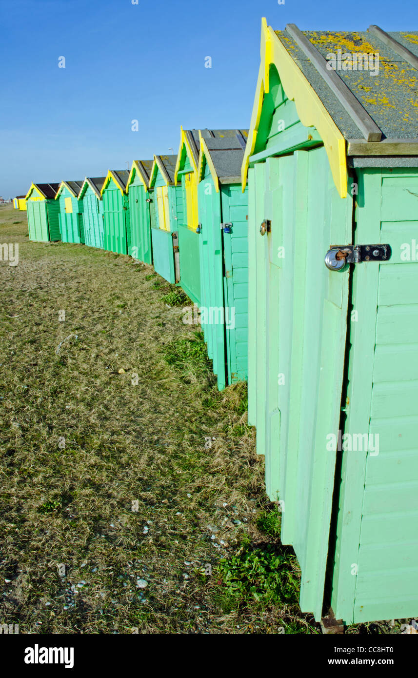 Fila di verde spiaggia capanne sulla spiaggia sulla costa sud dell'Inghilterra in Littlehampton, West Sussex, in Inghilterra, Regno Unito. Foto Stock