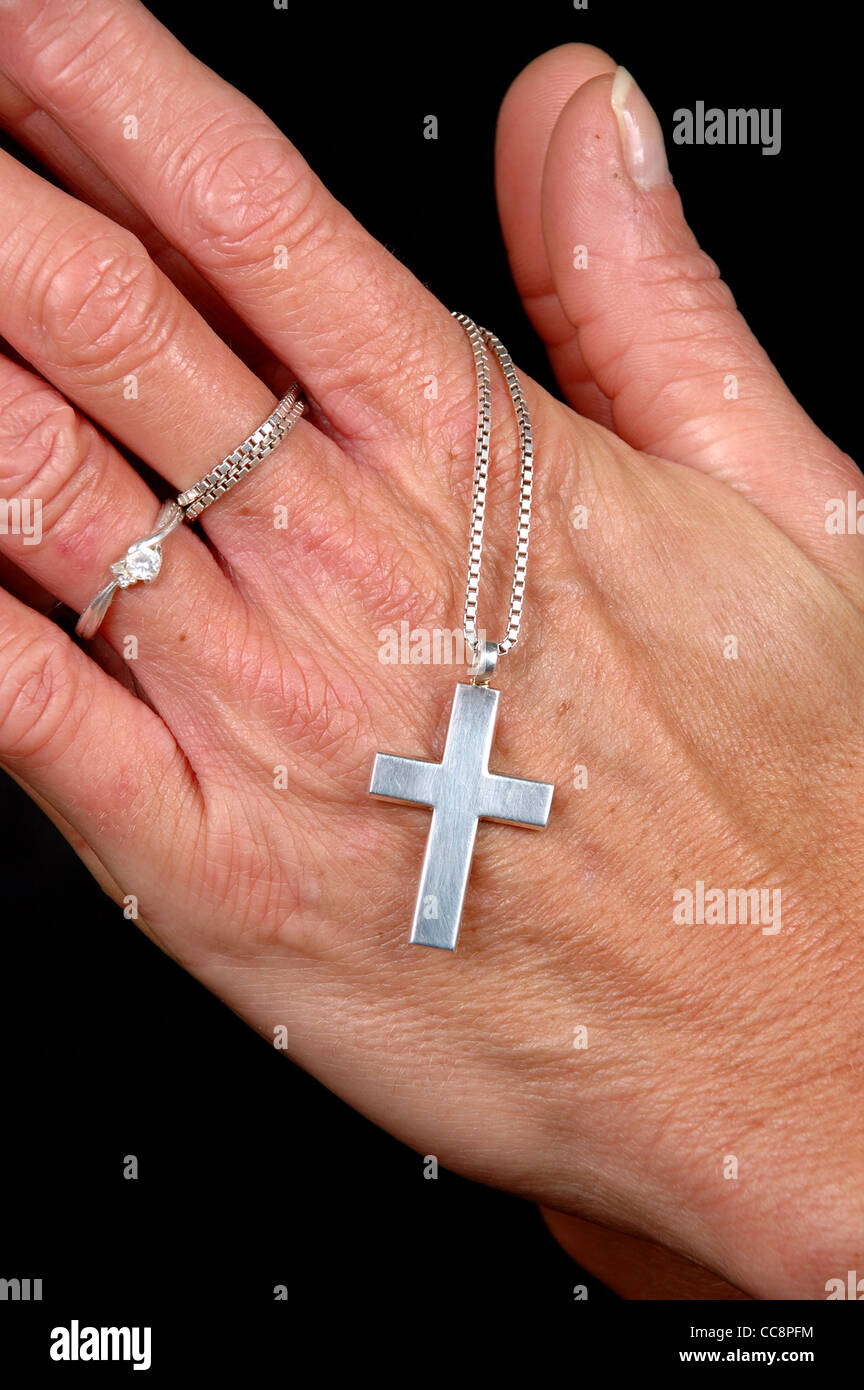 La donna sta pregando tenendo la sua croce. Nero su sfondo pulito. Foto Stock