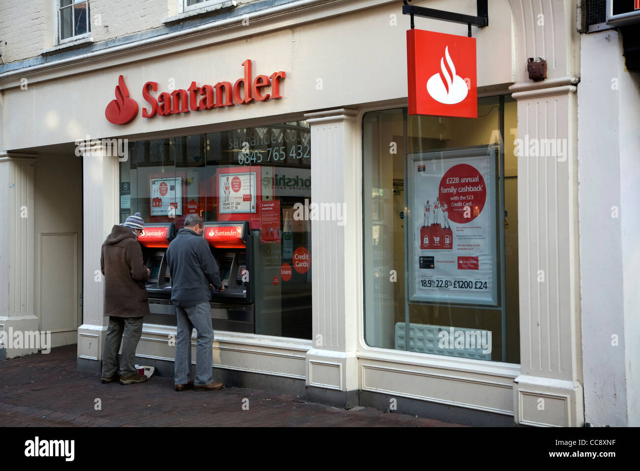 Due uomini utilizzare banca Santander ATM cash point machine Foto Stock
