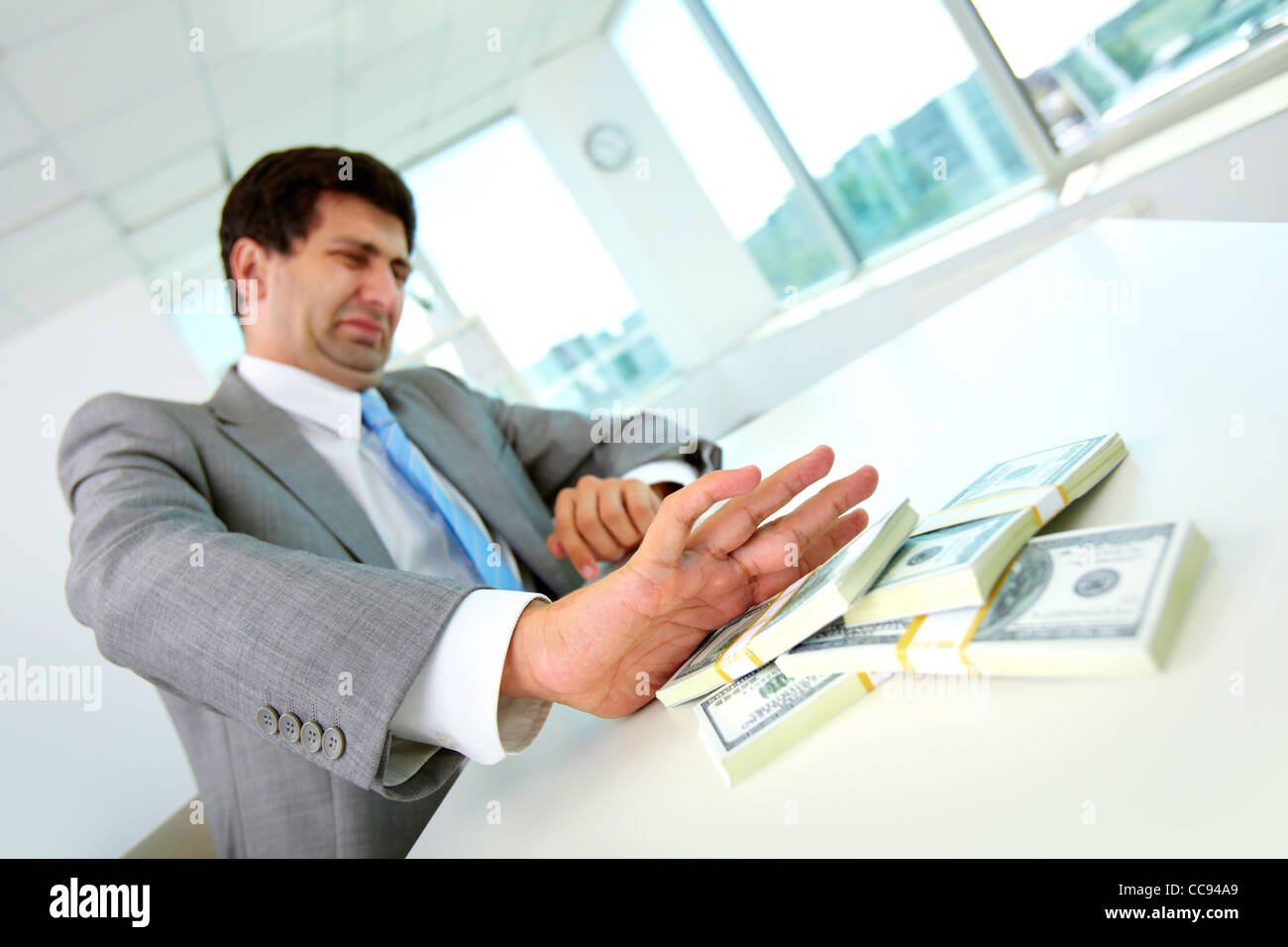 Immagine di disgustato dipendente di sesso maschile spostando le fatture del dollaro lontano e rifiutando di prendere tangenti Foto Stock