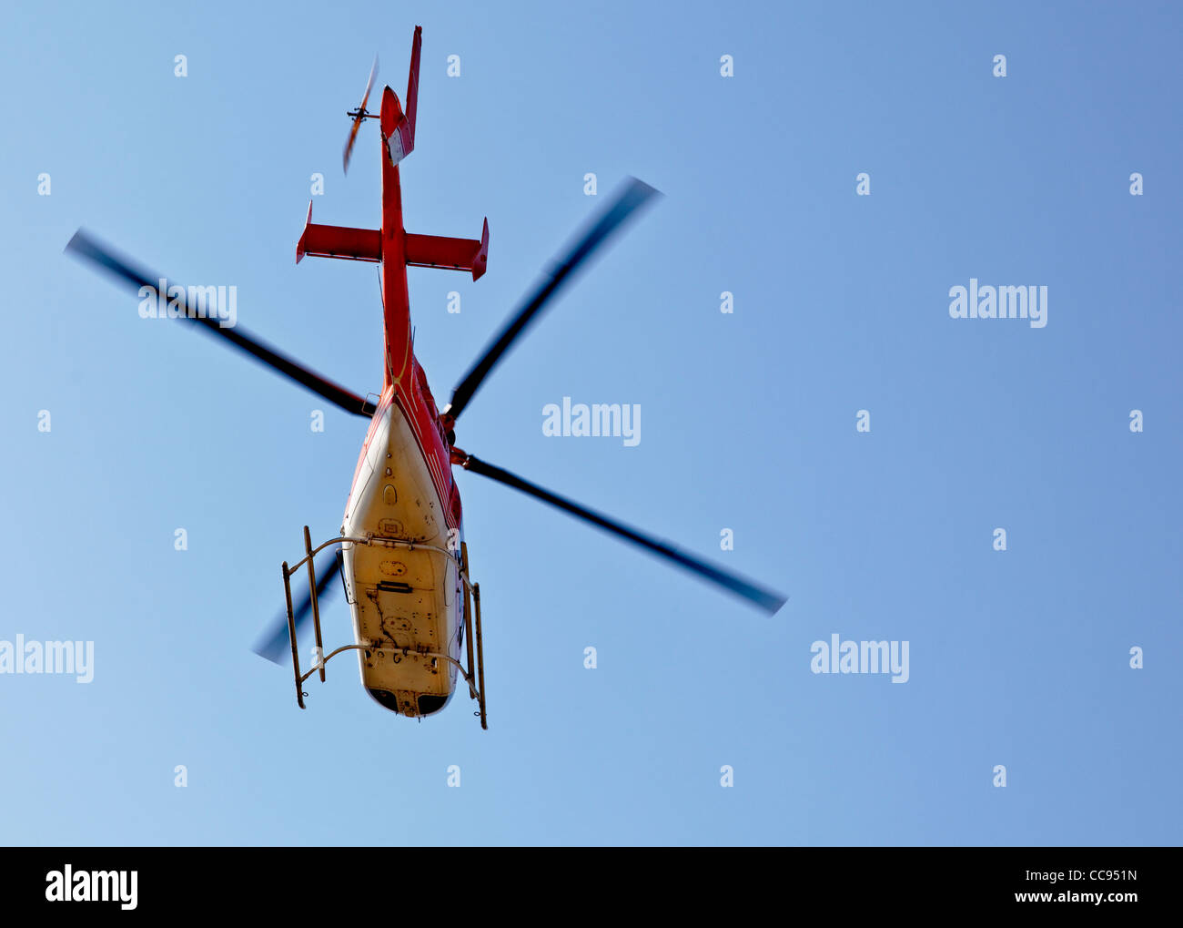 Orizzontale di un arancione bianco elicottero, qualsiasi orientamento, in volo con cielo blu chiaro Foto Stock