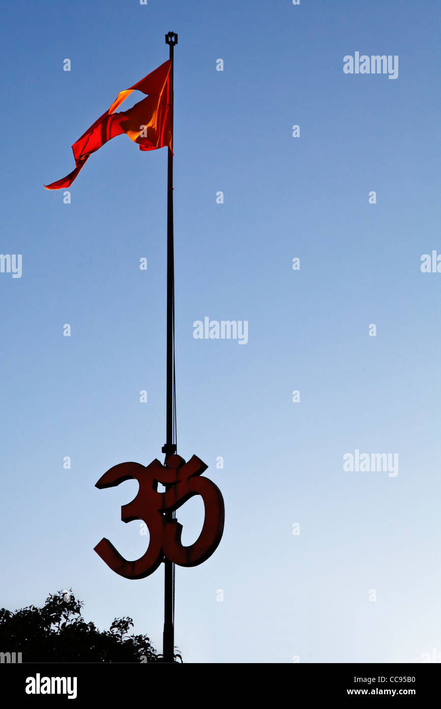 Silhouette di alberi e Hindu Om segno, bandiera pole e zafferano bandiera volare nel vento Foto Stock