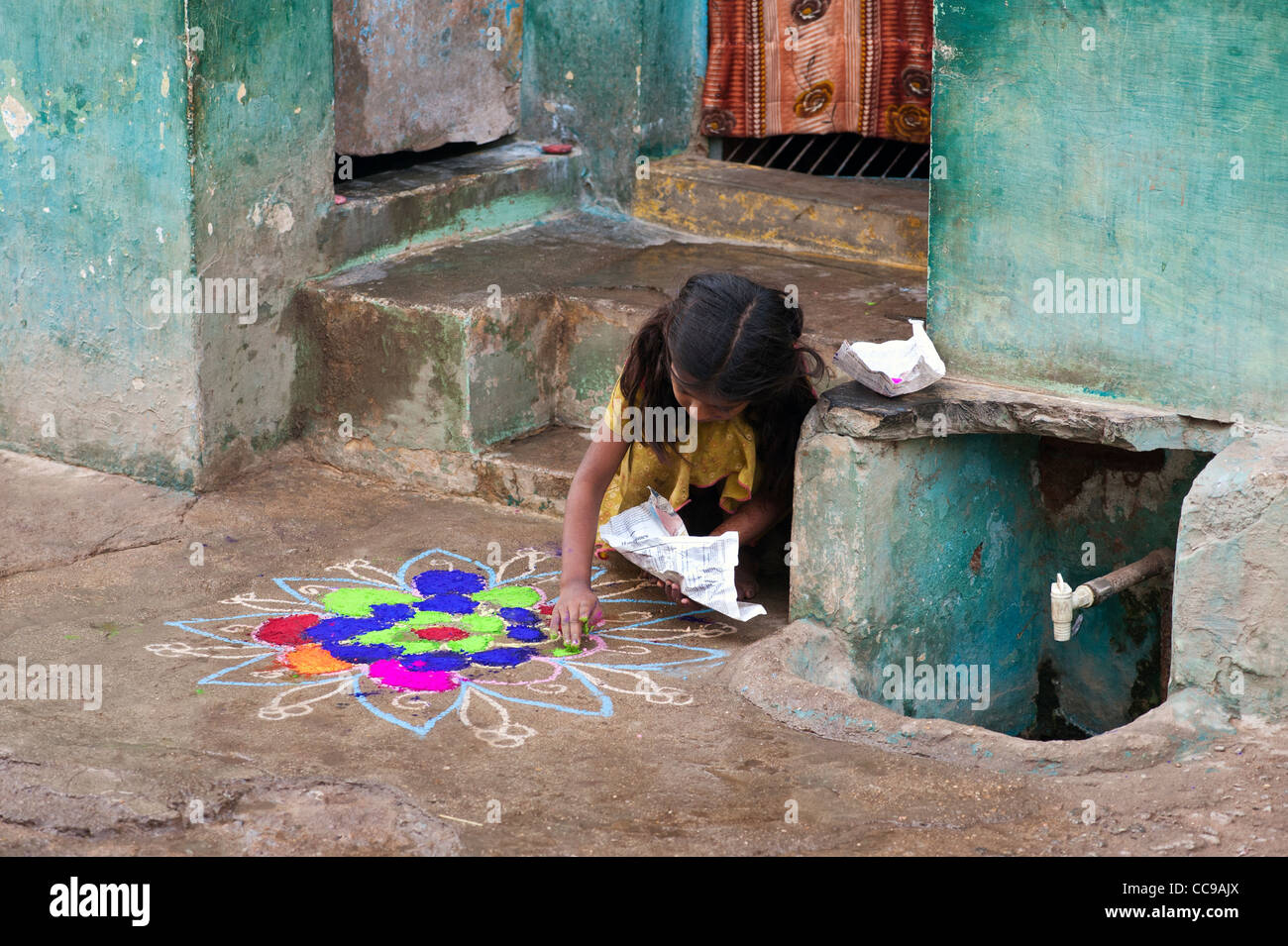 Giovane ragazza India facendo una Rangoli design festival al di fuori di casa sua in strada. Puttaparthi, Andhra Pradesh, India Foto Stock