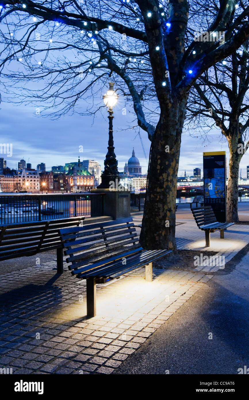 Queen's Walk, South Bank di Londra se 1 con banchi vuoti e l'illuminazione di una strada con lo skyline della città tra cui la cattedrale di St Paul Foto Stock