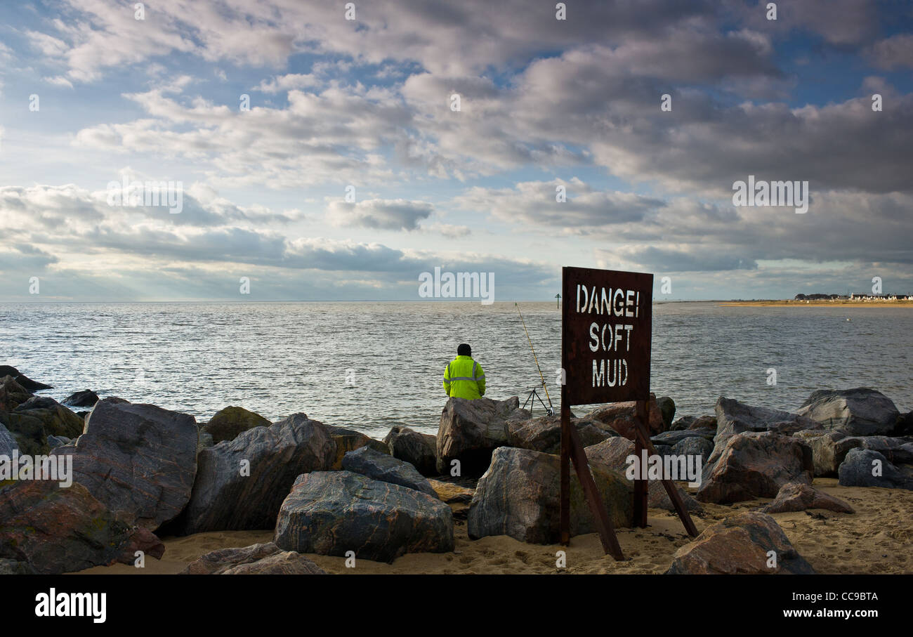 Un pescatore che pesca vicino al molo sulla spiaggia di Jaywick in Essex Foto Stock