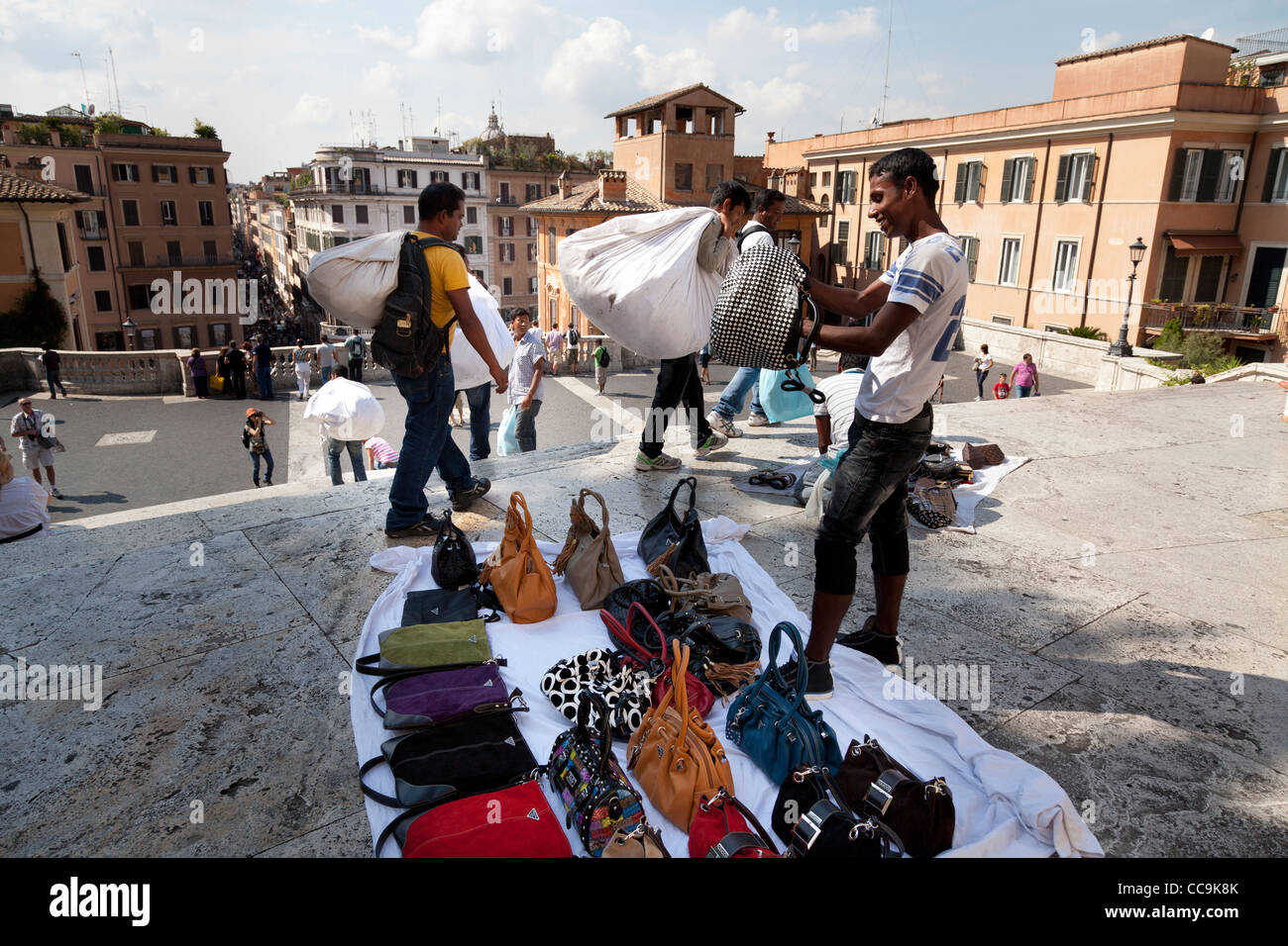 Itineranti di venditori ambulanti di vendita falsi designer merci indicate sui fogli per le strade di Roma Foto Stock