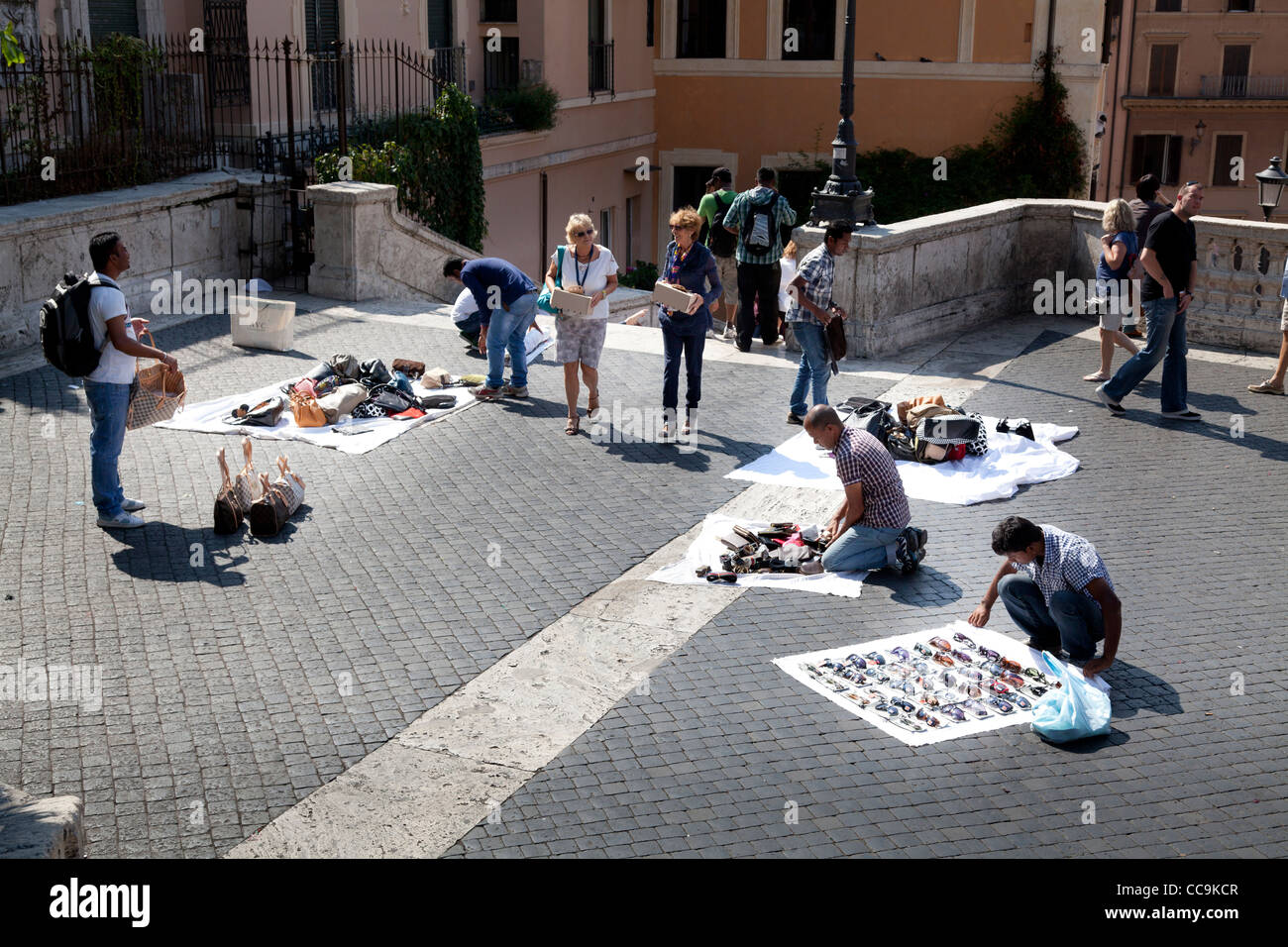 Itineranti di venditori ambulanti di vendita falsi designer merci indicate sui fogli per le strade di Roma Foto Stock