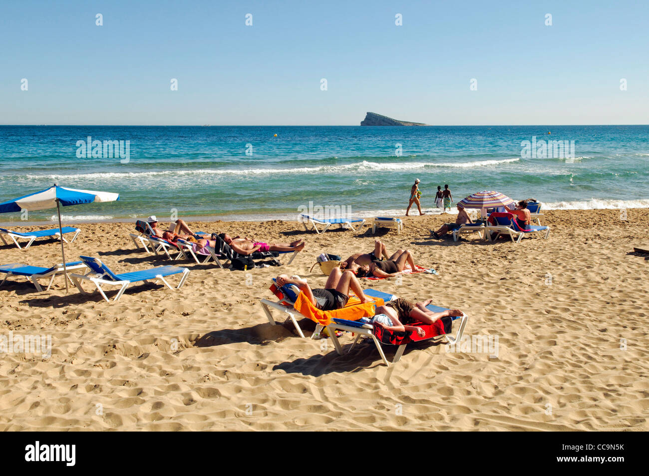 I turisti a prendere il sole sulla spiaggia di Levante in primavera a Benidorm, Spagna Foto Stock