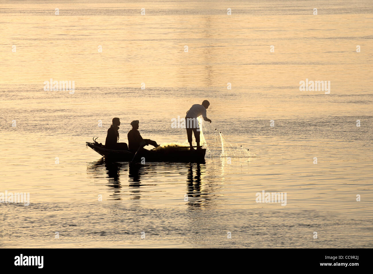 Sera colpo di tre uomini in una barca da pesca con reti nel fiume Nilo in Egitto Foto Stock