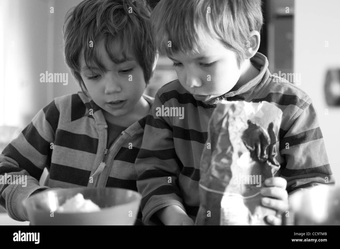 Due bambini di cottura di una torta al cioccolato insieme Foto Stock