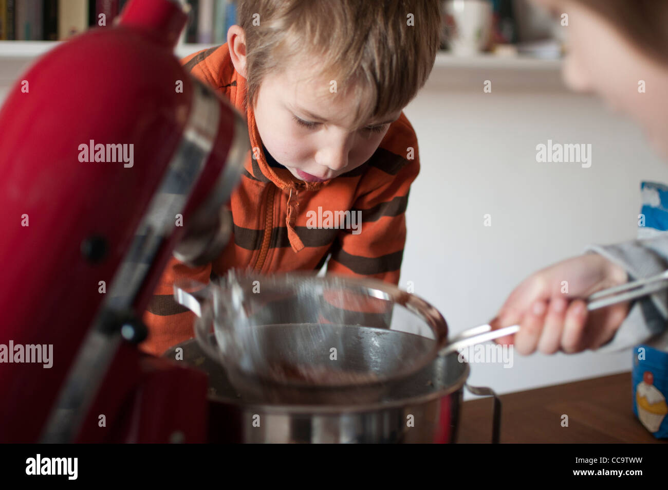 Due bambini di cottura di una torta al cioccolato insieme Foto Stock