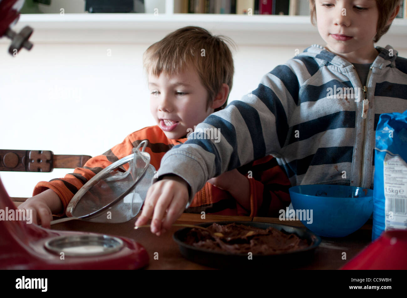 Due bambini di cottura di una torta al cioccolato insieme Foto Stock