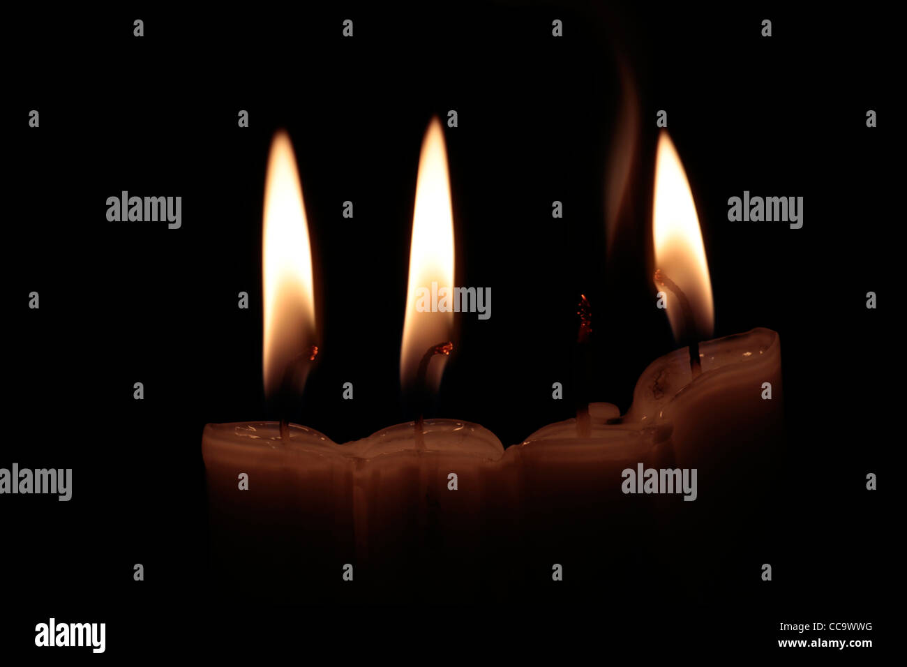4 candele: 3 di loro masterizzazione con incandescente stoppini, una candela spegnerà, ancora incandescente, con fumo, su sfondo nero Foto Stock
