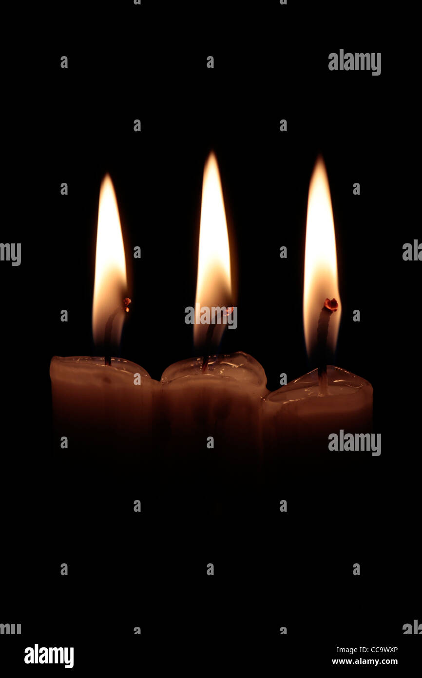 3 candele accese con incandescente stoppini, su sfondo nero, verticale shot Foto Stock