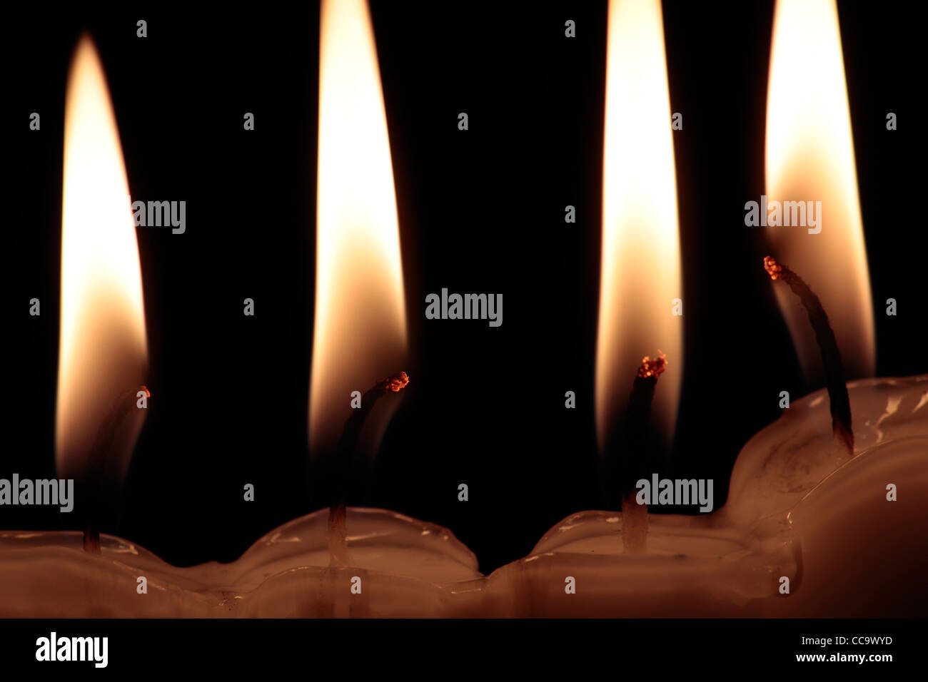 Close up di 4 candele accese con incandescente stoppini, su sfondo nero Foto Stock