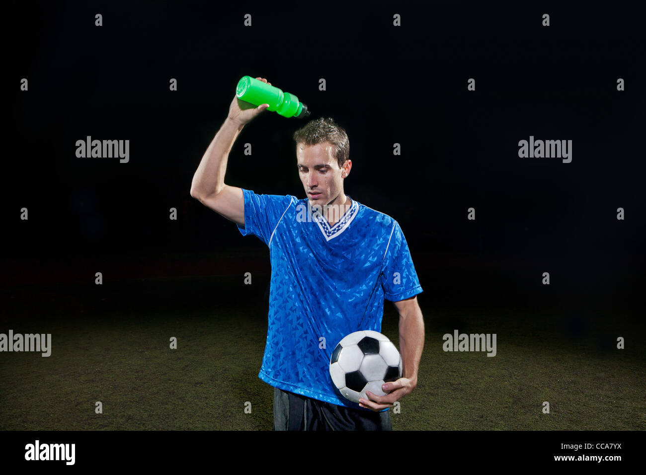 Giovane giocatore di calcio versando acqua di se stesso al passo Foto Stock