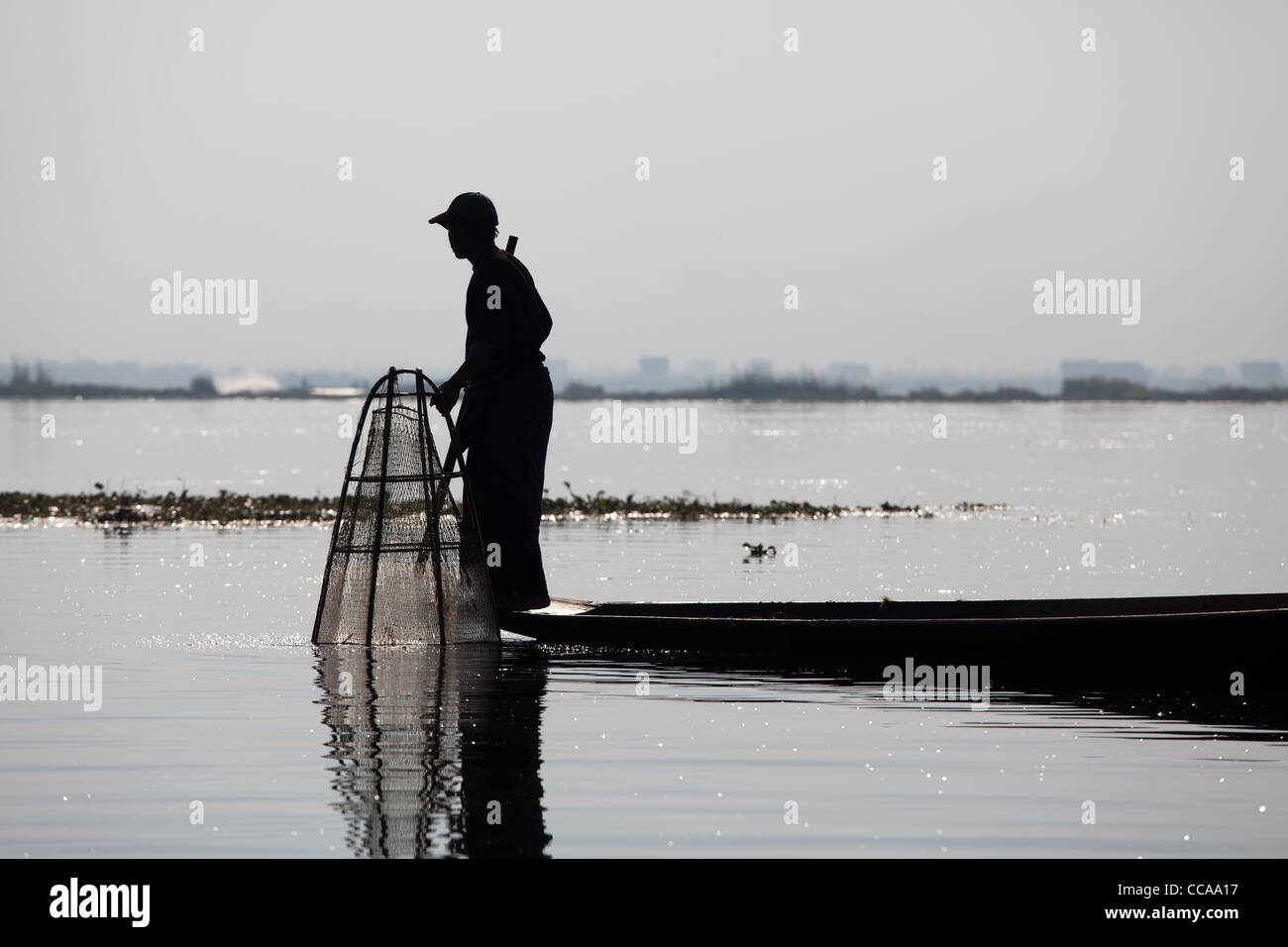 Ammaliante tribal pescatore sul Lago Inle in Birmania. Singolare tecnica di gamba-barca a remi e coniche Tutina in rete. Foto Stock