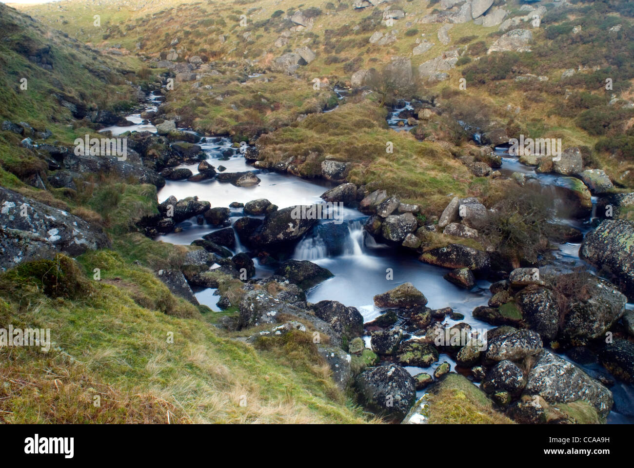 Il boulder disseminate di facciata ripida Valle dell'Oriente Dart River al di sopra di due ponti, Parco Nazionale di Dartmoor, Devon, Inghilterra. Foto Stock