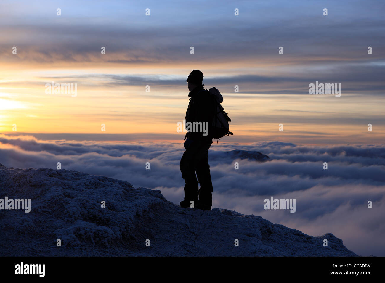 Walker a guardare il tramonto e inversione di cloud in prossimità del vertice del Beinn Ghlas, uno dei Ben Lawers Munros gruppo Foto Stock