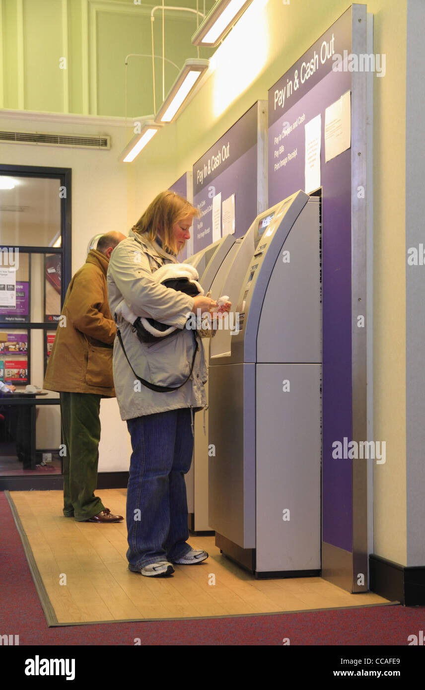 Persone prelevare denaro contante formano una macchina ATM in una Natwest Bank, Eastbourne, East Sussex, Inghilterra. Foto Stock
