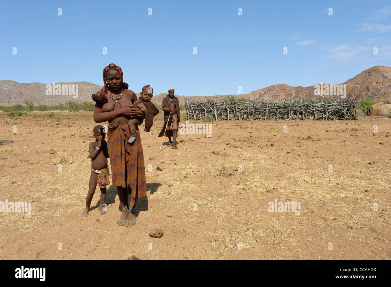 Himba donna, i bambini e l'uomo di fronte alla centrale di enclosure di bestiame . Kaokoland, Namibia settentrionale. Foto Stock