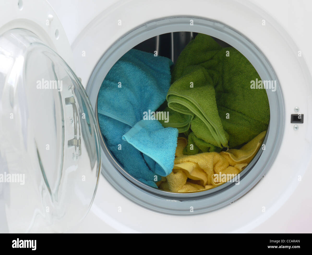 Asciugamani colorati all'interno del cesto della macchina di lavaggio Foto Stock