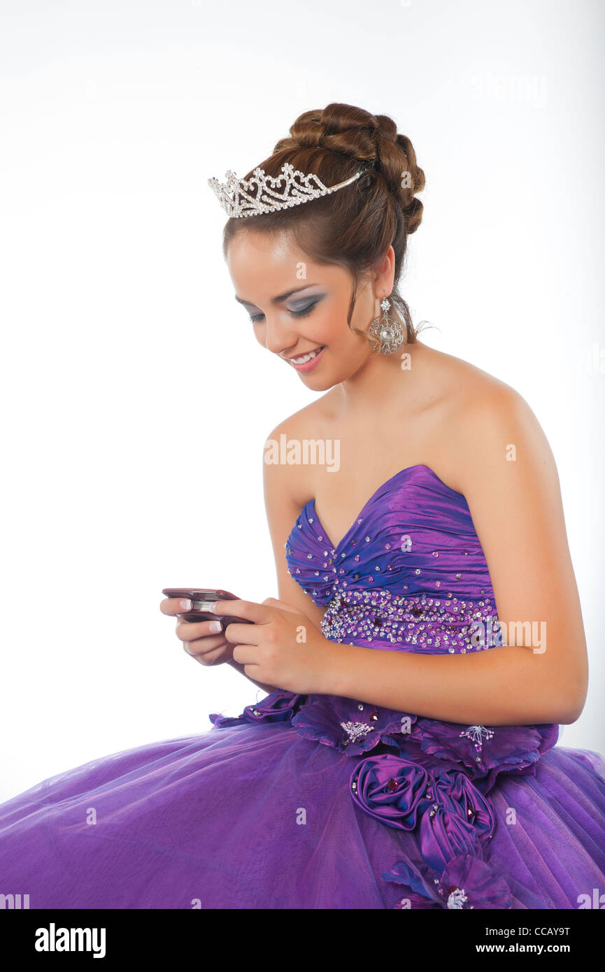 Felice giovane ragazza in abito formale del suo 15. compleanno sms sul cellulare Foto Stock