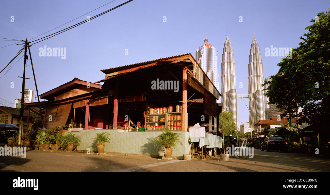 Il tramonto e la notte scende come le Torri Petronas incombono su di Kampung Baru nella città di Kuala Lumpur in Malesia in Estremo Oriente Asia sud-orientale. Città Travel Foto Stock