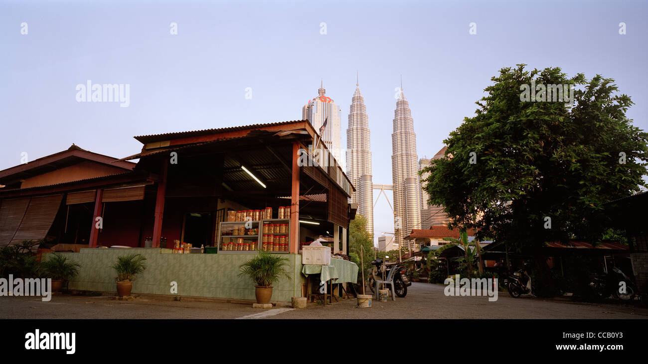 Il tramonto e la notte scende come le Torri Petronas incombono su di Kampung Baru nella città di Kuala Lumpur in Malesia in Estremo Oriente Asia sud-orientale. Città Travel Foto Stock