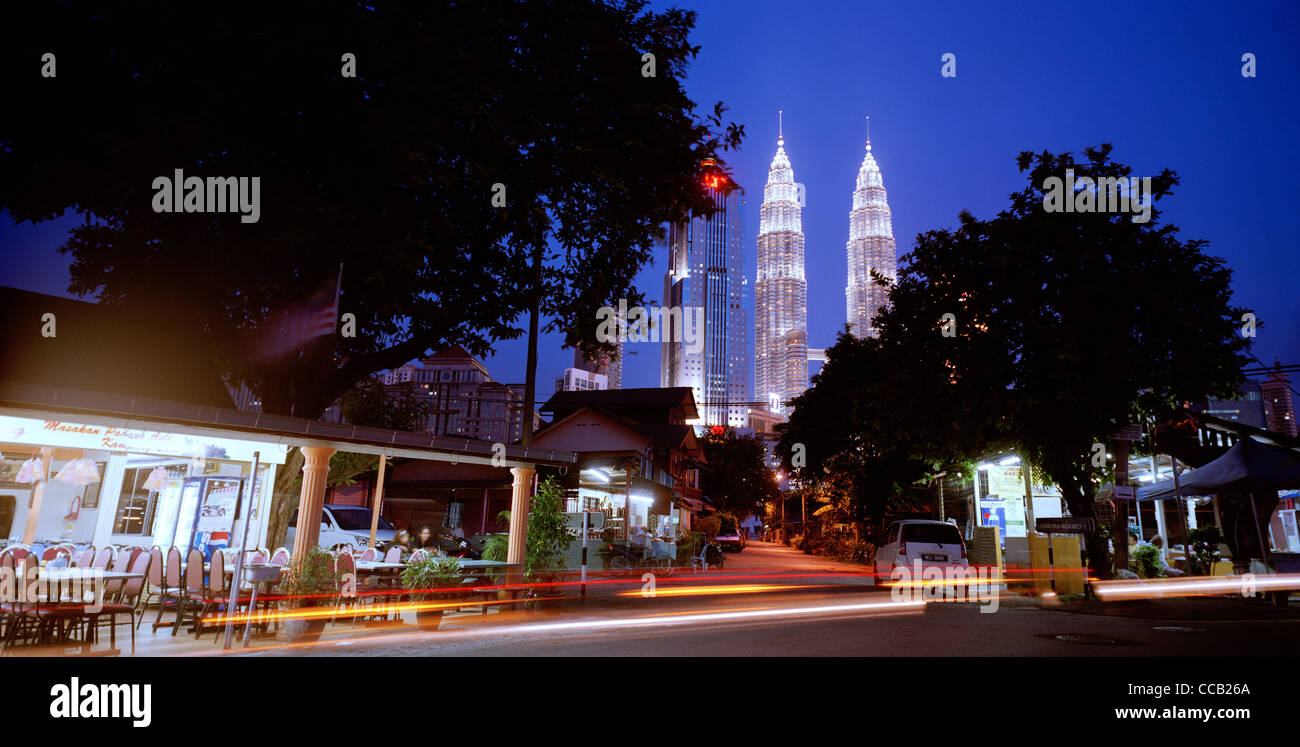 Il tramonto e la notte scende come le Torri Petronas incombono su di Kampung Baru nella città di Kuala Lumpur in Malesia in Estremo Oriente Asia sud-orientale. Città Travel Foto Stock