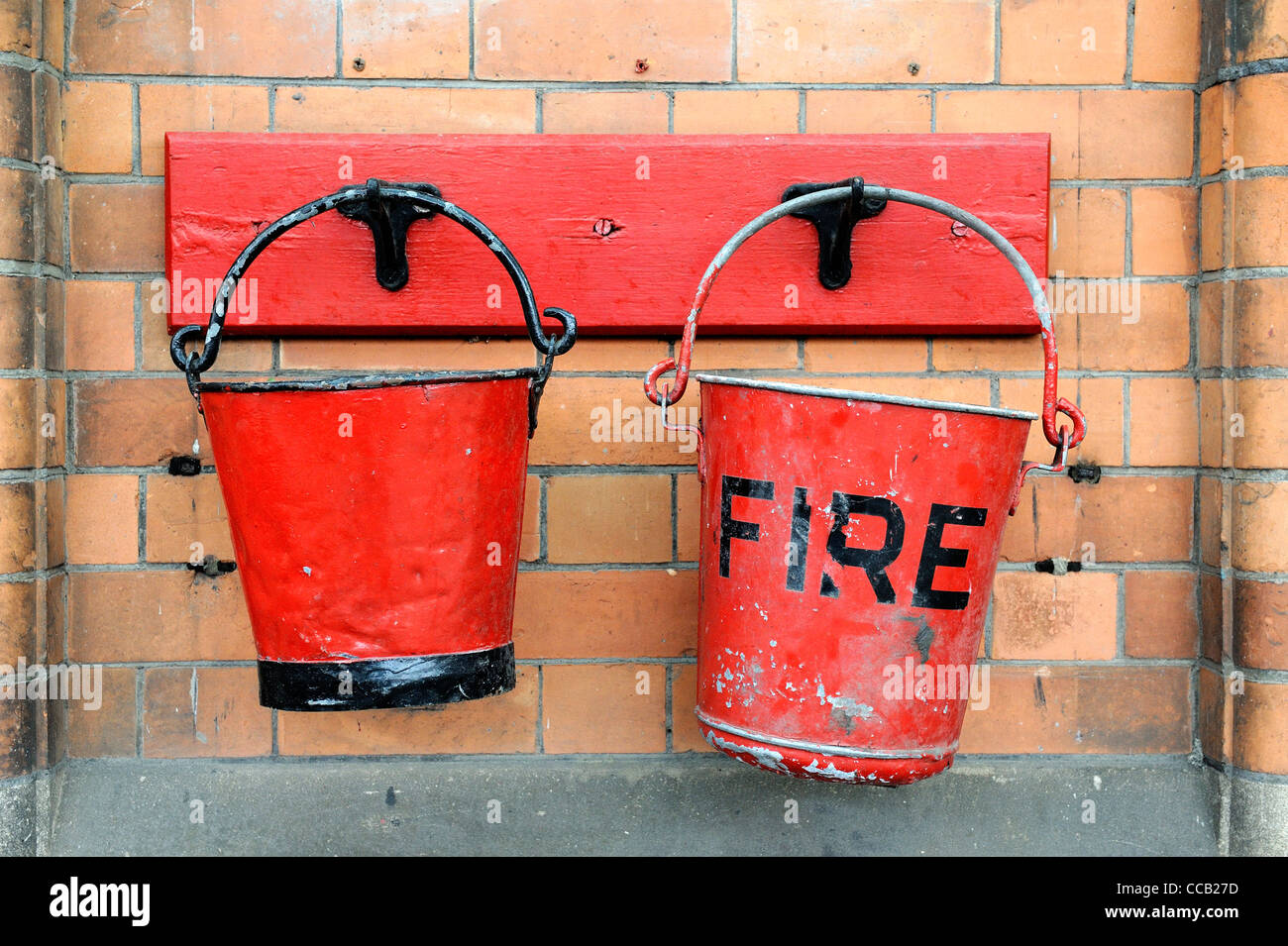 Rosso fuoco Secchi legato a una stazione ferroviaria parete England Regno Unito Foto Stock