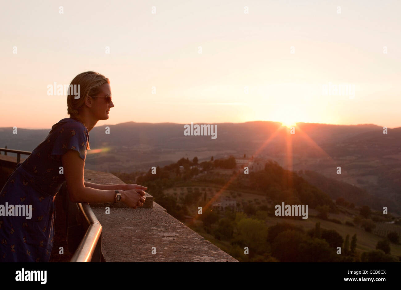 Una giovane donna si affaccia sulla campagna come il sole tramonta. Todi, Umbria, Italia. Foto Stock
