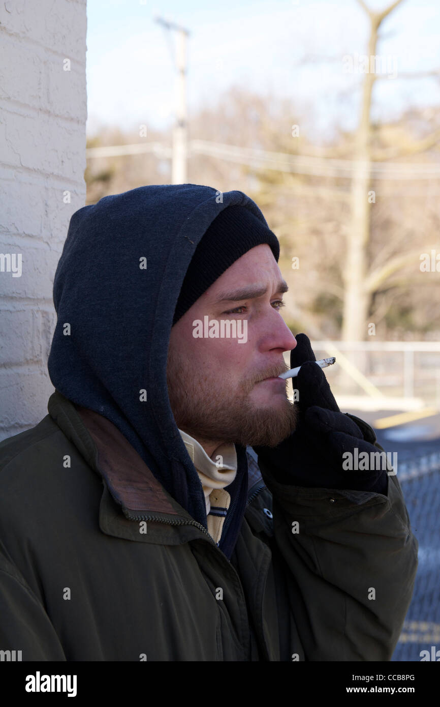 Senzatetto uomo Sigaretta fumare sul freddo giorno d'inverno. Foto Stock