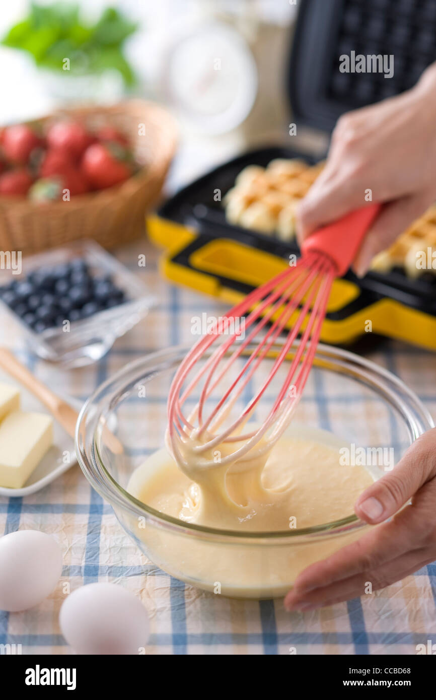 Le mani umane sbattere Waffle pastella Foto Stock