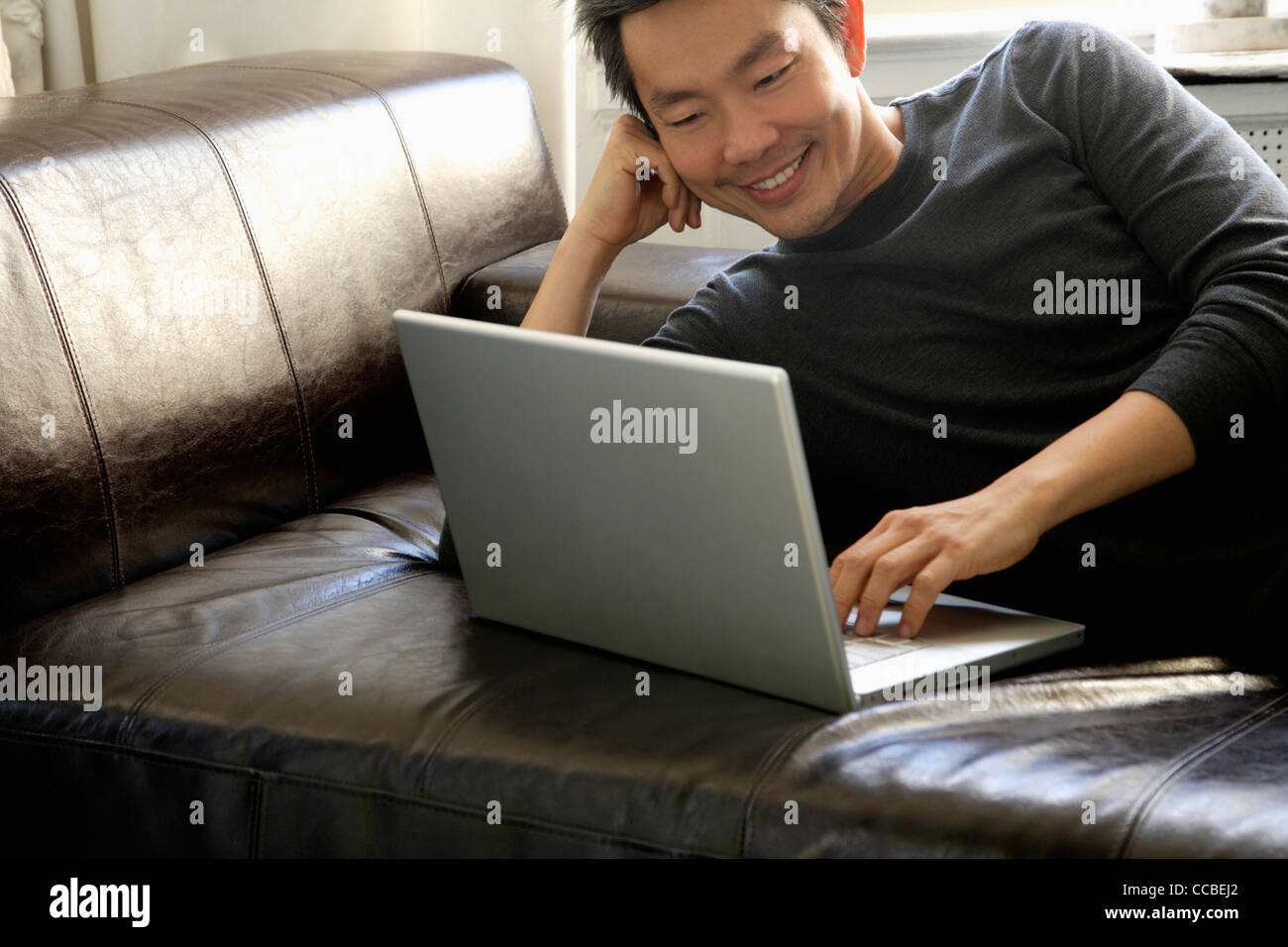 L'uomo posa sul divano con lap top Foto Stock