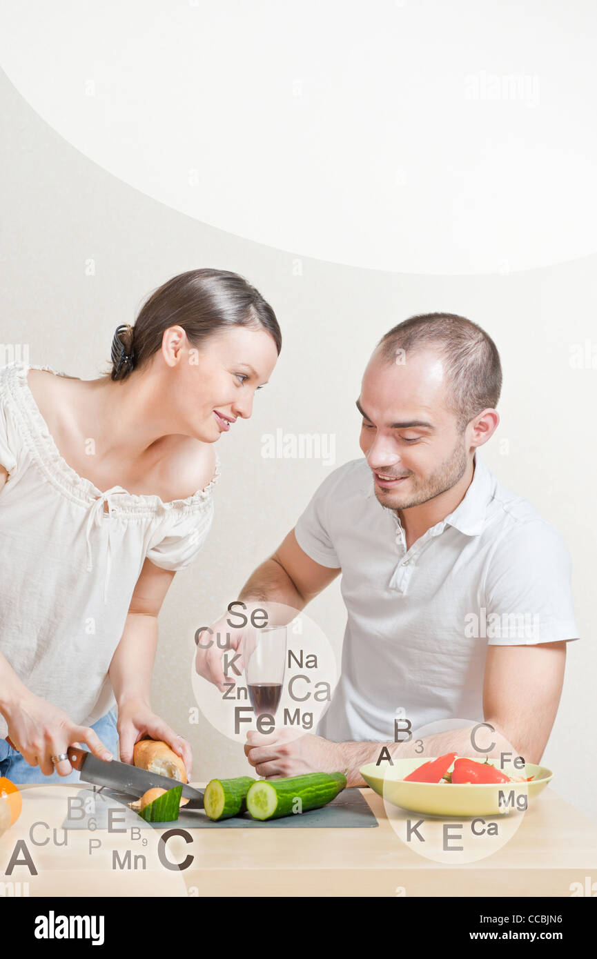 Giovane coppia adorabile la cottura di una dieta bilanciata. Grande copyspace. Vitamine e microelementi i simboli sono intorno a loro. Foto Stock