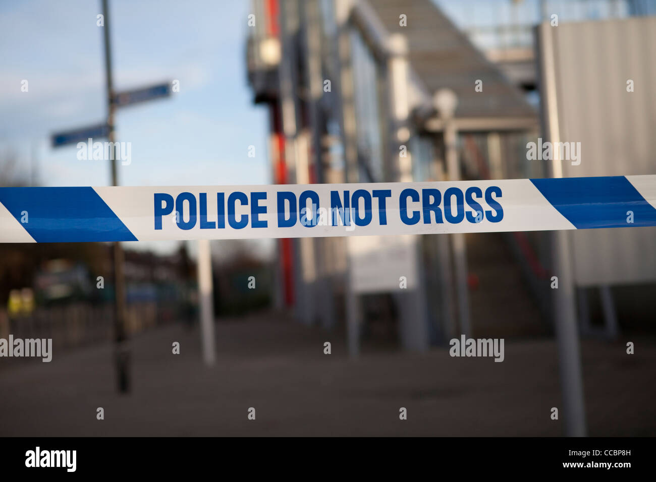 Bianco e blu nastro di polizia con la polizia non si incrociano con DLR station sullo sfondo Foto Stock
