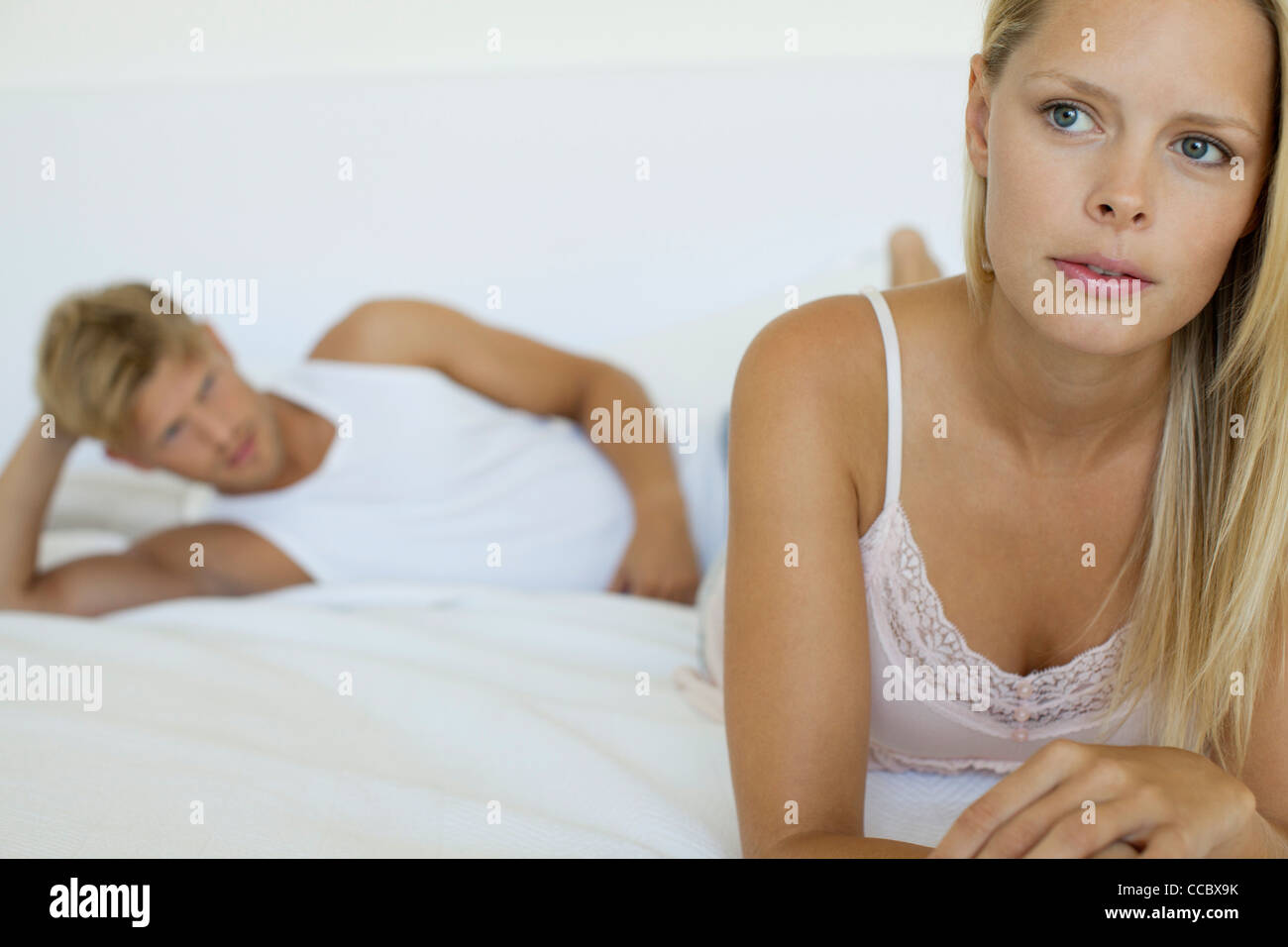 Donna rilassante sul letto, l'uomo che giace in background Foto Stock