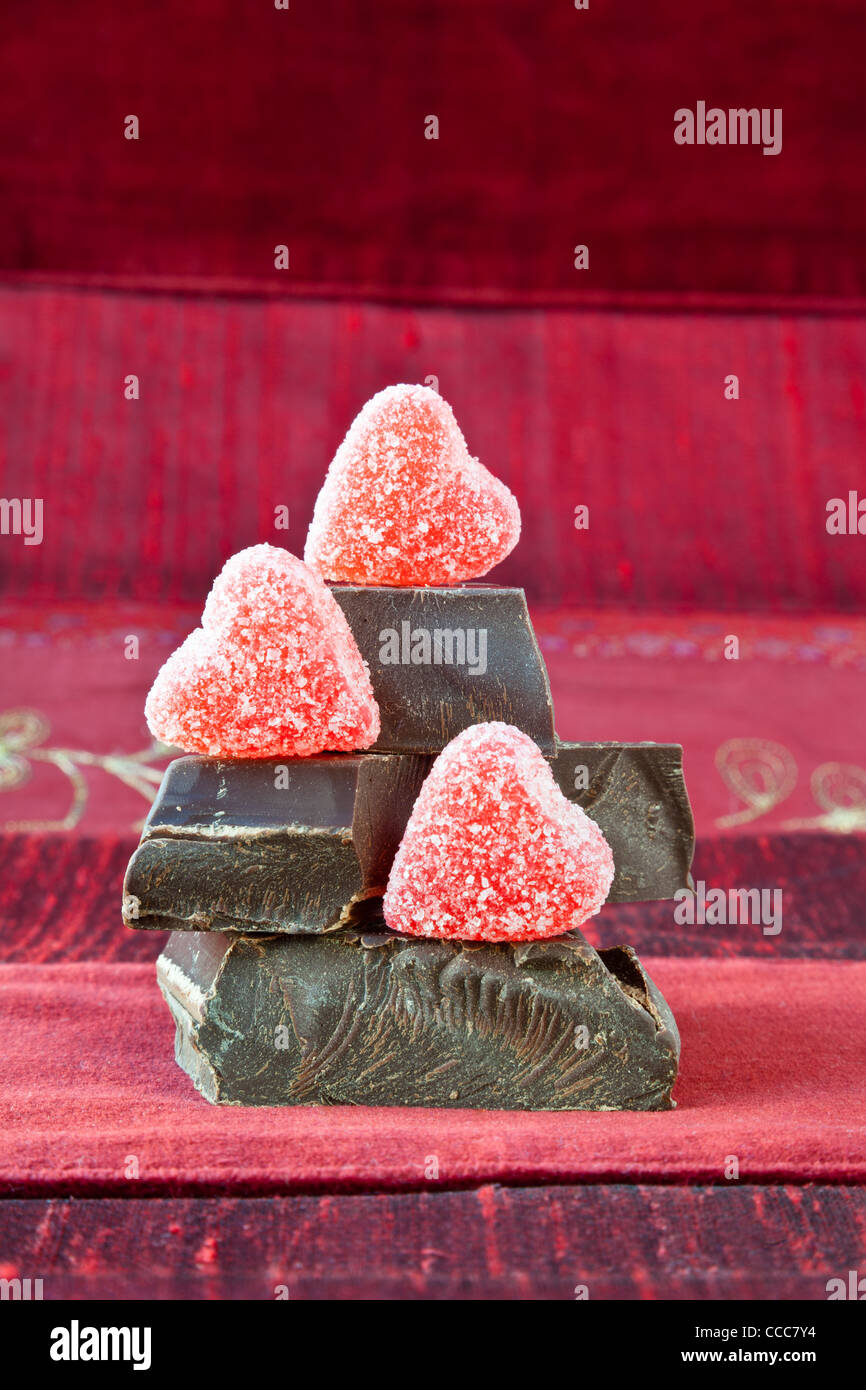 Jelly (gummy) rivestite di zucchero candito cuori disposti sulla sommità della pila di spessore gourmet dark chocolate bar chunk. Foto Stock