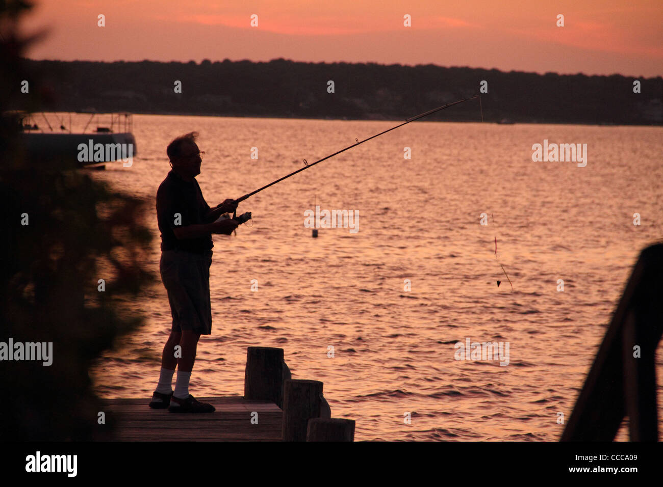 Senior pesca maschio al tramonto off di pier orizzontale Foto Stock