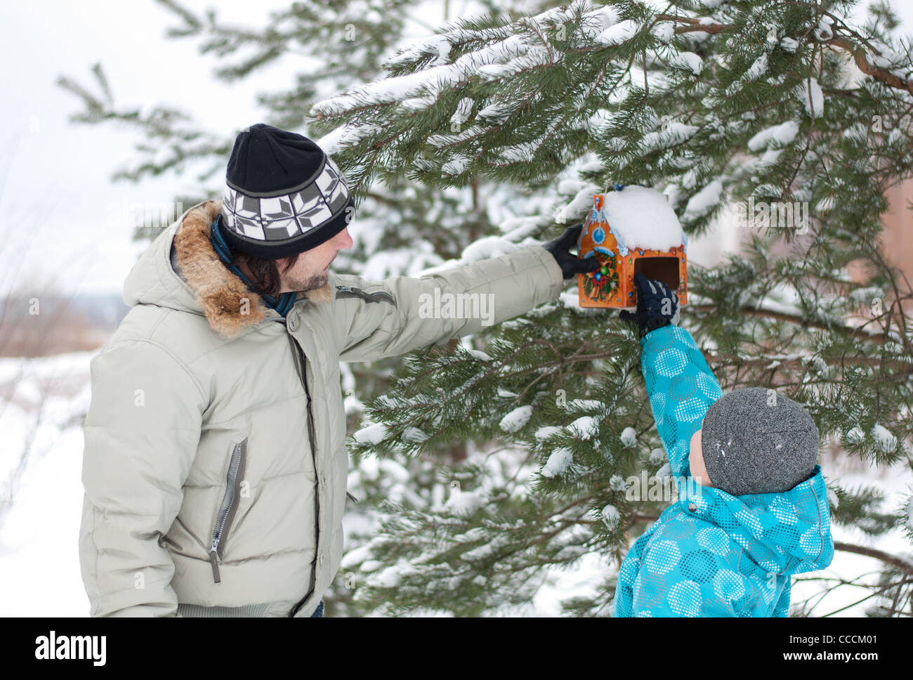 Padre figlio famiglia due uomo bambino inverno 7 8 anni coperta di neve giacca hat cap feed di alimentazione parco foresta sospesa Zelenograd Mo Foto Stock